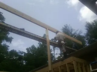 Carpenter setting a ridge beam over a new addition frame — Ice Dam Removal by Roofing Brothers in Wrightsville Beach