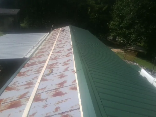 Old rusted panels beside newly installed green metal roofing — Wind Damage Roof Repair by Roofing Brothers in Wrightsville Beach