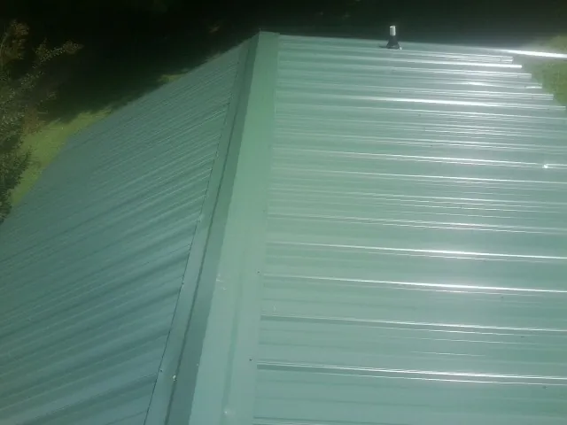 New green metal panels meeting at the ridge of a roof — Flat Roof Repair work by our crew in Wrightsville Beach