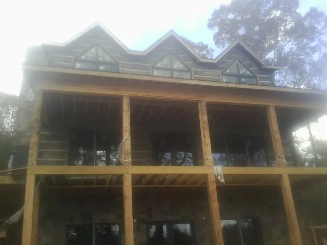 Dormers and porch framing on a large log home under construction — Roof Coating work by our crew in Wrightsville Beach