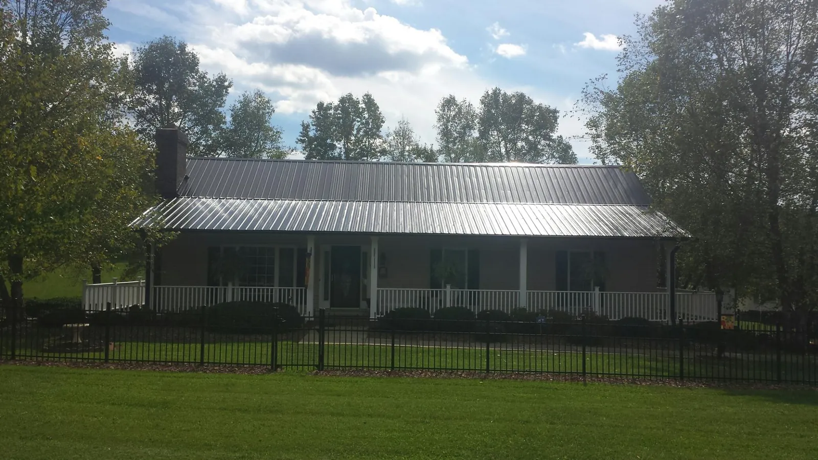 Gray metal roof on a brick ranch with a full width front porch — Gutter Guard Installation work by our crew in Wrightsville Beach