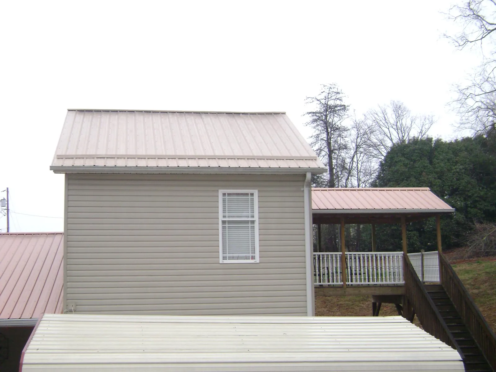 Tan metal roofs on a two story addition and attached porch, from a Roof Replacement job in Wrightsville Beach