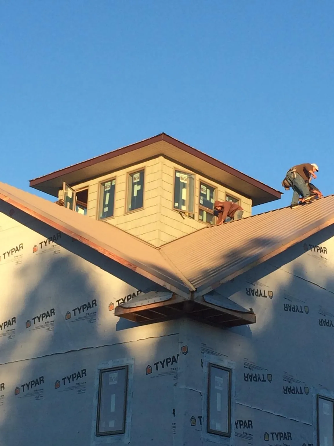 Roofers working around a rooftop cupola on a new metal roof at sunset — Roof Waterproofing in Wrightsville Beach by Roofing Brothers
